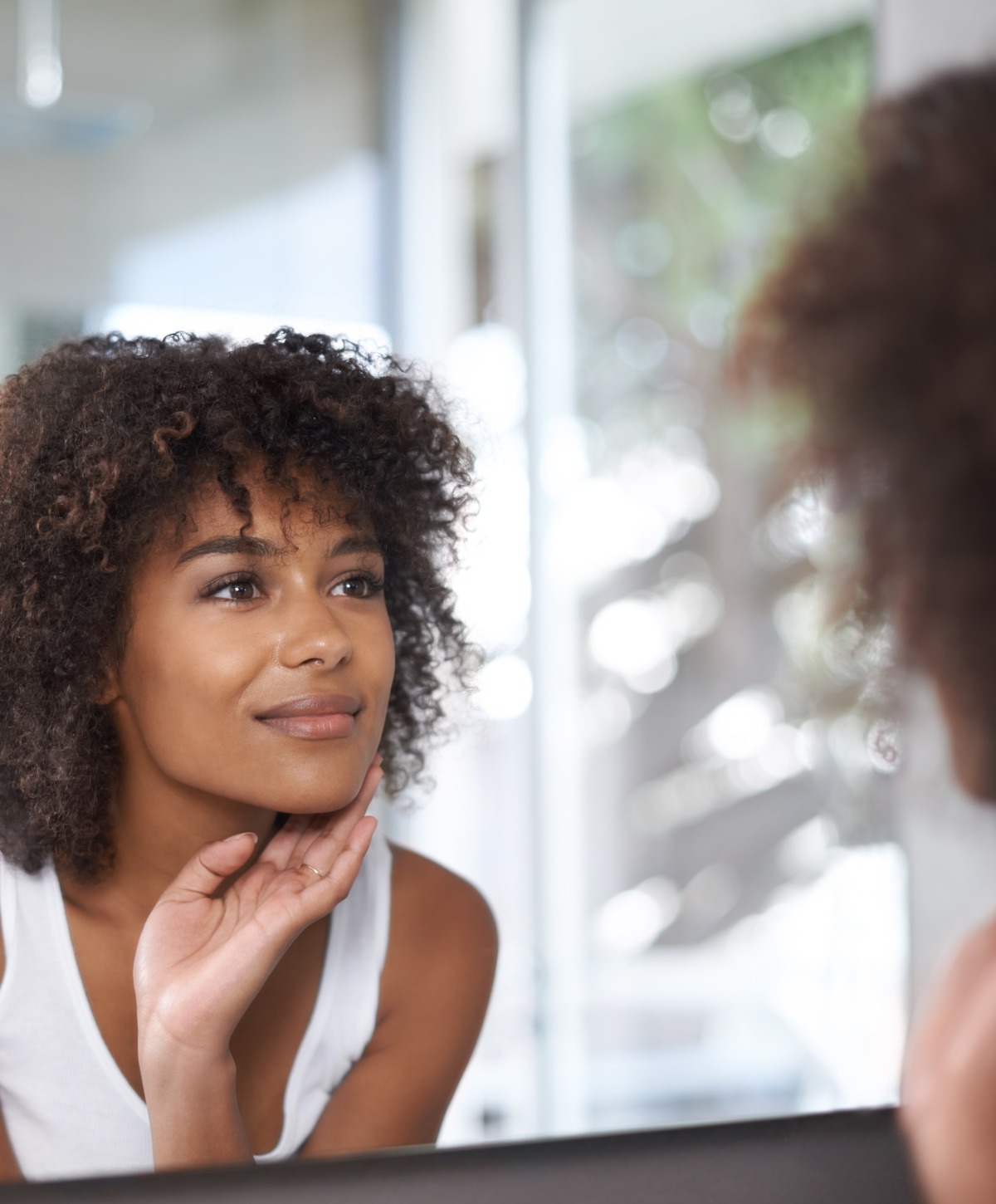 woman looking at her reflection in a bathroom mirror